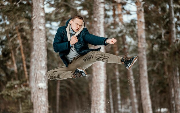 Foto gratuita l'uomo che salta all'aperto nella natura durante l'inverno