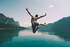 Free photo man jumping with joy by a lake
