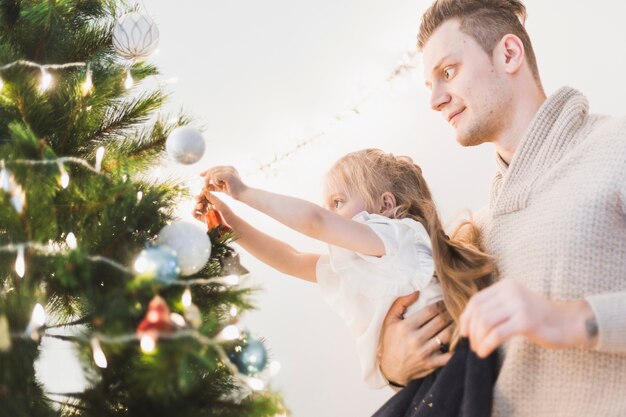 Man and kid decorating illuminated christmas tree together