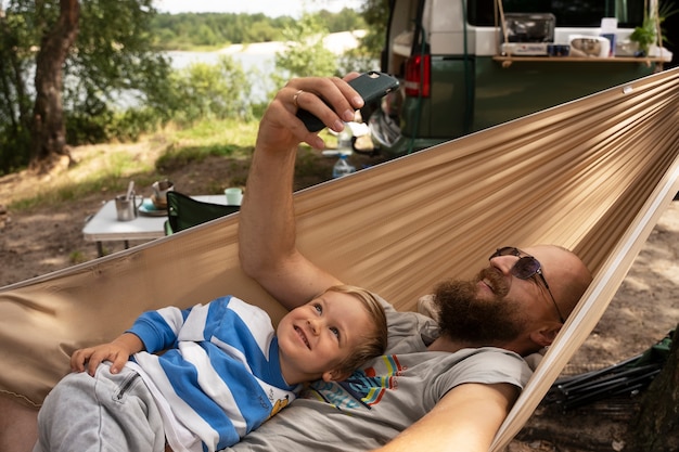 Uomo e bambino che prendono selfie nella vista laterale dell'amaca