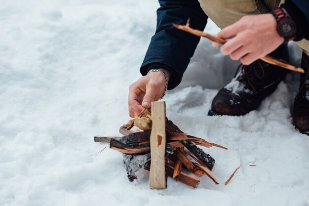 Man kindle bonfire in winter snowy weather