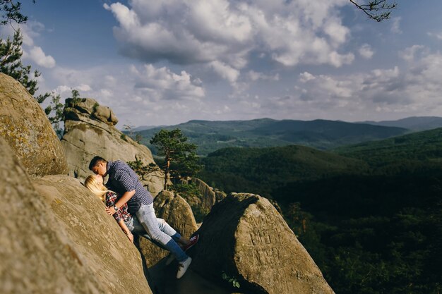 Man kisses woman standing before beautiful mountain landscape
