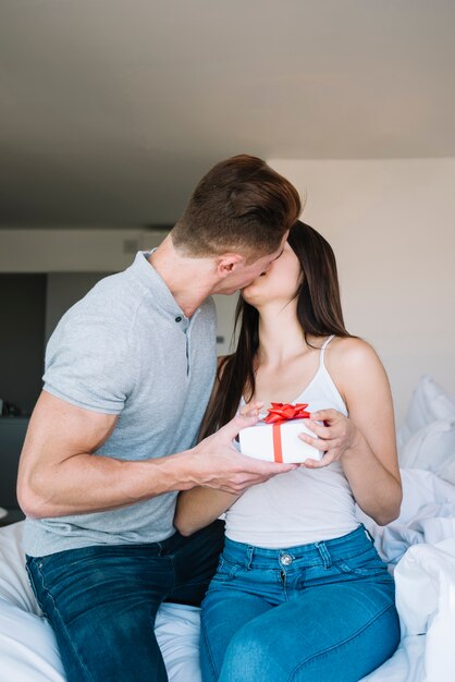 Man kissing and giving gift box to woman