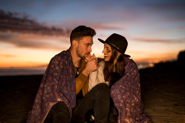 海岸に座っている女性の手をキスする男