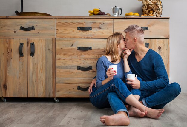 Man kissing his girlfriend on the cheek while sitting on the floor