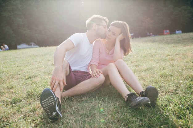 Man kissing his partner sitting on the lawn