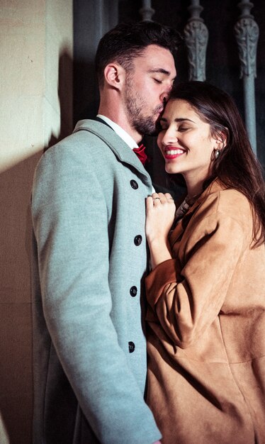 Man kissing pretty woman on forehead in street