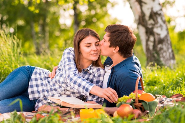 Man kissing woman on cheek in forest