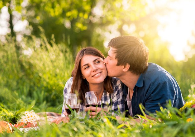 Мужчина целует женщину в щеку на пикнике