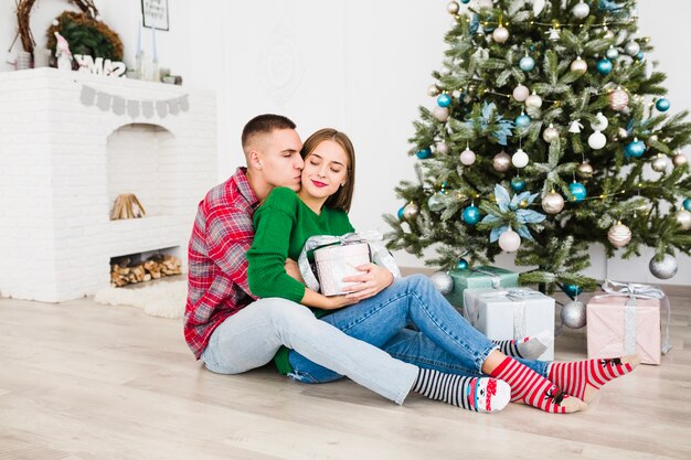 Man kissing woman next to christmas tree