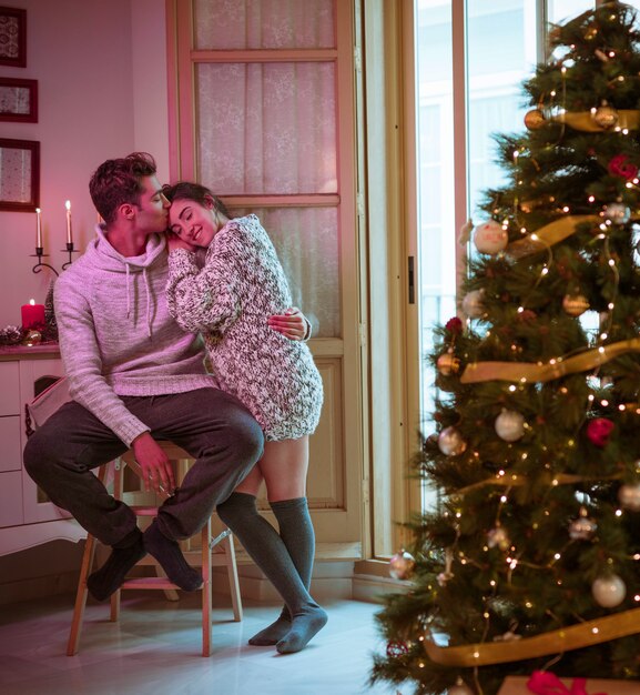 額にクリスマスツリーの近くに男がキスする男