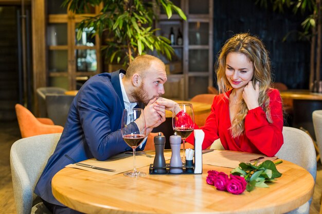 Man kissing woman hand at table in restaurant 