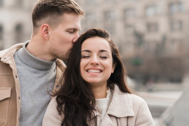 Man kissing woman on the head outside