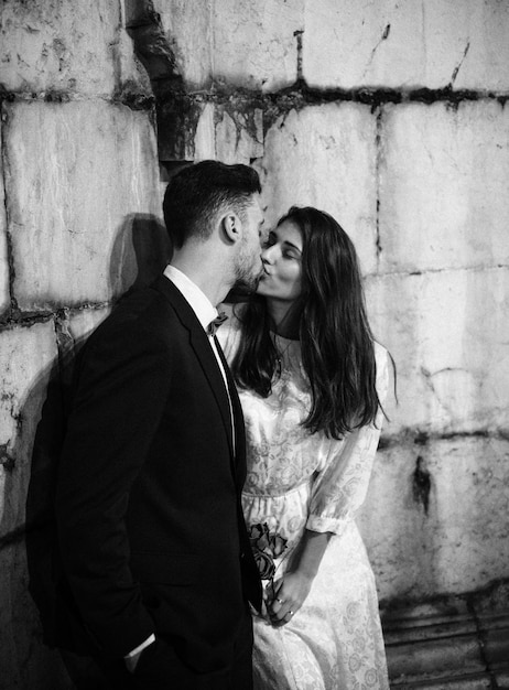 Free photo man kissing woman leaning on building wall