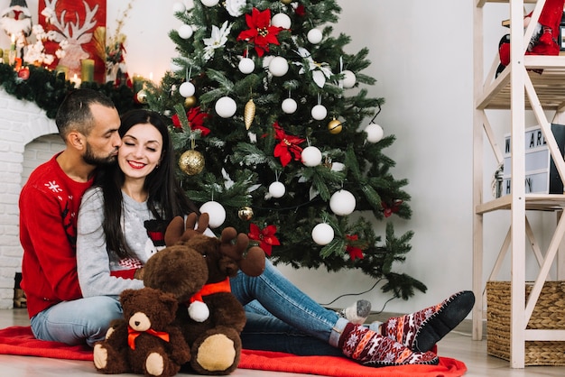 Free photo man kissing woman near soft toys