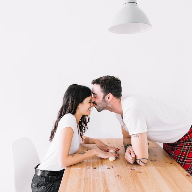 Man kissing woman during rolling dough