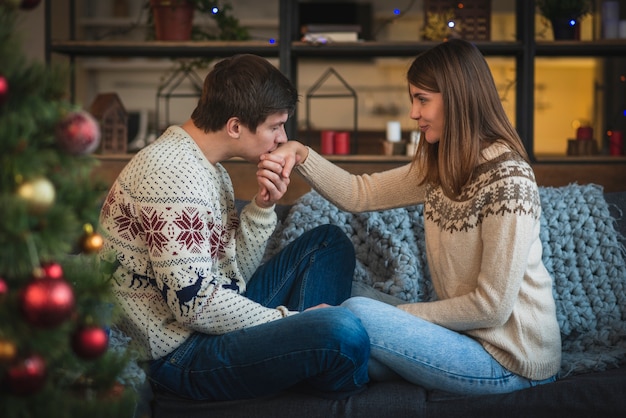 ソファの上の女性の手にキスをする男性