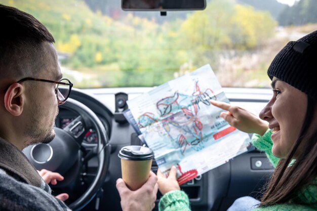 車の中に座って紙の地図を持って見ている男性と女性