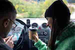 Free photo a man and lady holding and looking at paper map sitting inside car