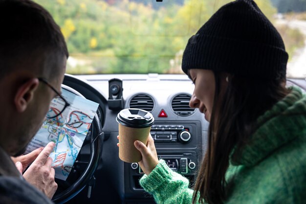 A man and lady holding and looking at paper map sitting inside car