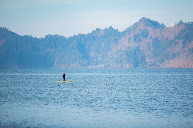 Мужчина на озере катается на доске.