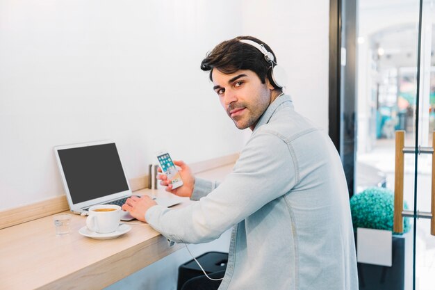 スマートフォンとコーヒーを持つラップトップの男