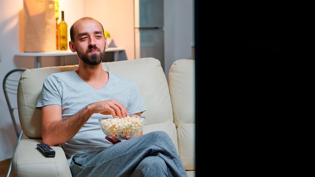 L'uomo a tarda notte nel suo appartamento guardando l'intrattenimento televisivo