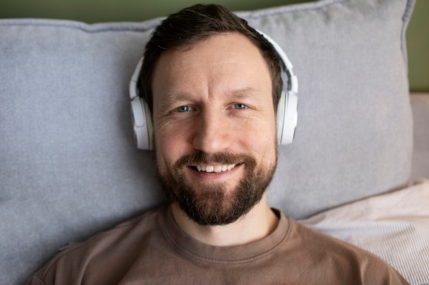 Free photo man laying on bed listening to music