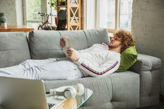 Man laying on the couch and reading a magazine