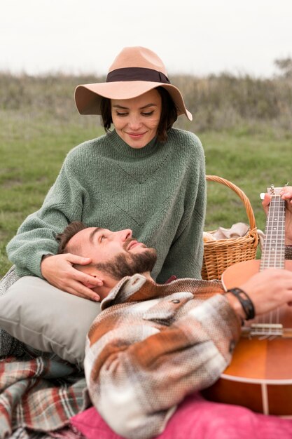 Man laying on girlfriend's lap and playing guitar