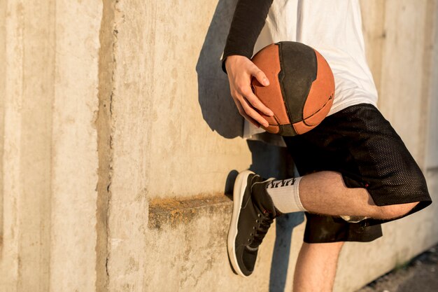 Man leaning against a wall with basketball