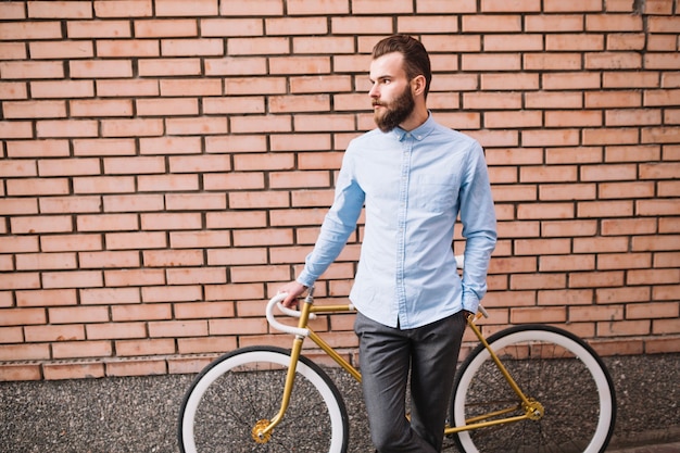 Man leaning on bicycle near brick wall