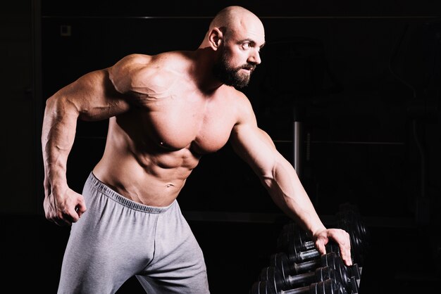 Man leaning on dumbbell rack