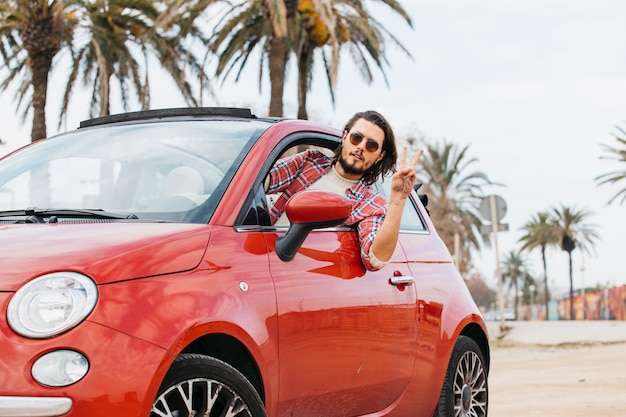 Man leaning out from car and showing peace gesture