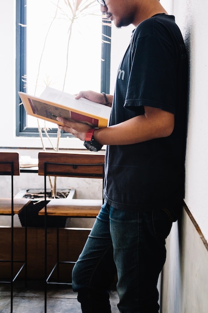 Man leaning on wall and reading book