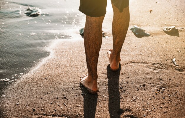 Man legs on sand shore near water 