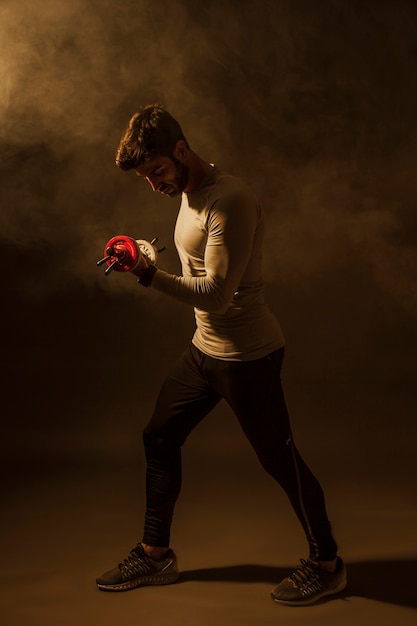 Man lifting dumbbells in dark room