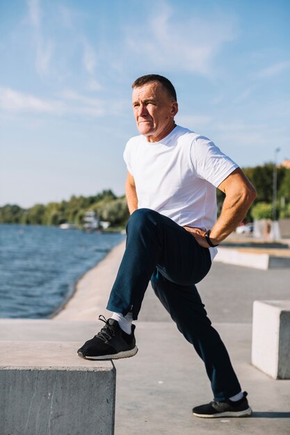 Man lifting his foot up by a lake