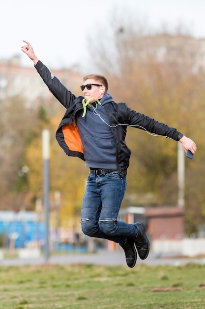 Man listening to music on earphones while jumping outside
