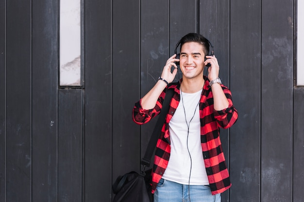 Man listening to music in front of wooden wall