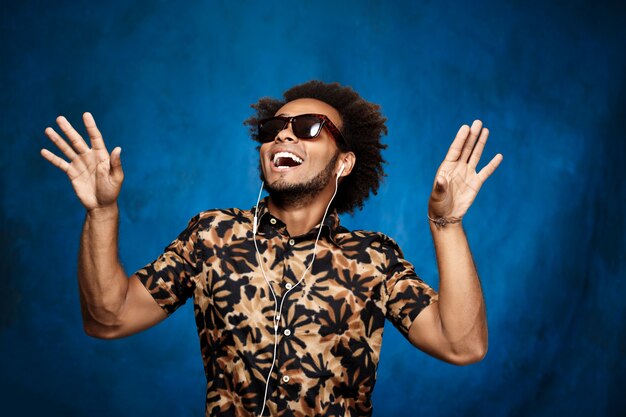 Man listening music in headphones, dancing over blue surface