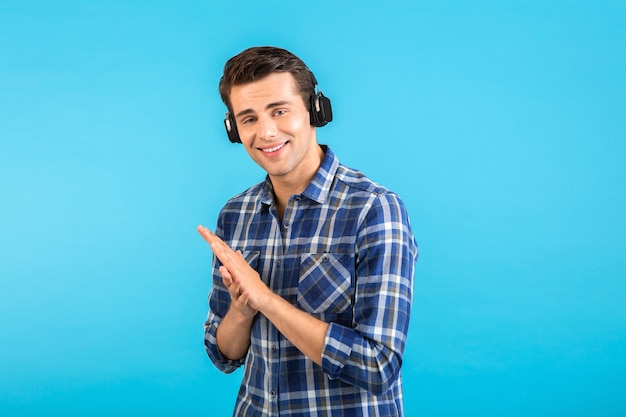 파란색으로 격리된 현대적인 스타일의 행복한 감정적 분위기를 즐기는 무선 헤드폰으로 음악을 듣는 남자