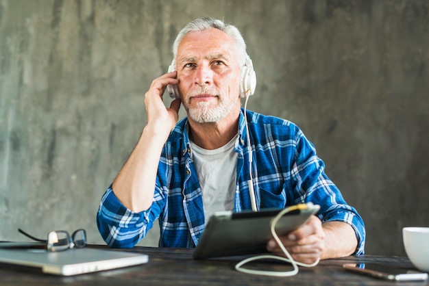 Man listening through headphone attached on digital tablet