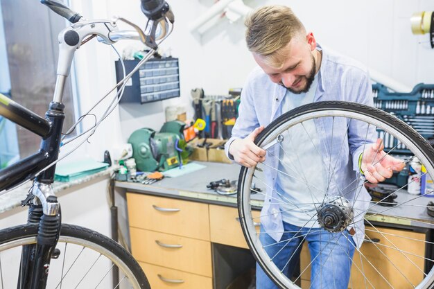 Man looking at bicycle tire in workshop