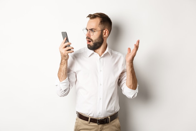 Человек смотрит в замешательство на мобильном телефоне после разговора, стоя озадаченный Копией пространства