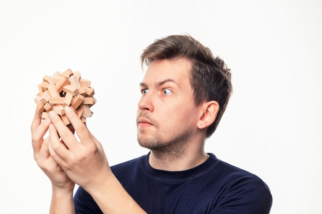 man looking confused at wooden puzzle.