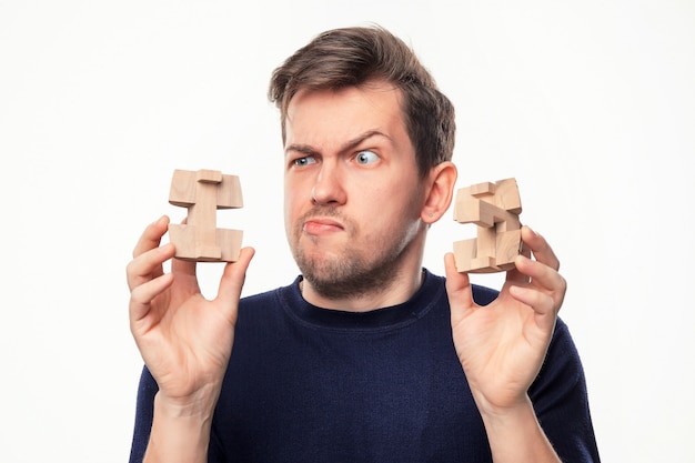 Free photo man looking confused at wooden puzzle.