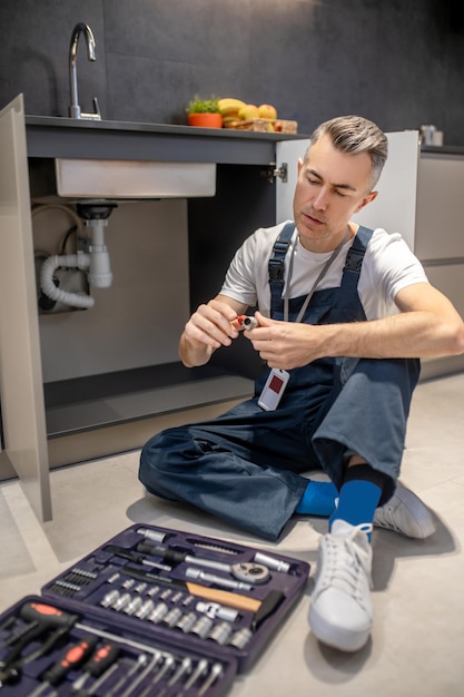 Free photo man looking at detail sitting on floor