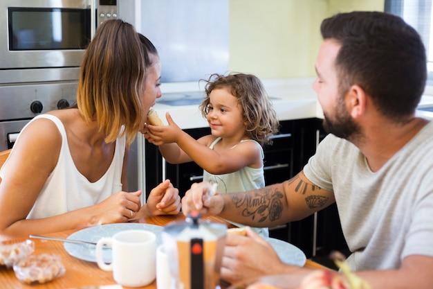 man looking at girl feeding bread to her mother