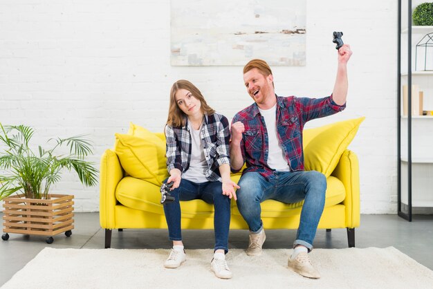 Man looking at her girlfriend shrugging after losing the video game at home